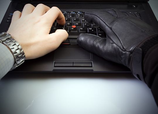 Security concept with businessman and hacker hands on laptop keyboard